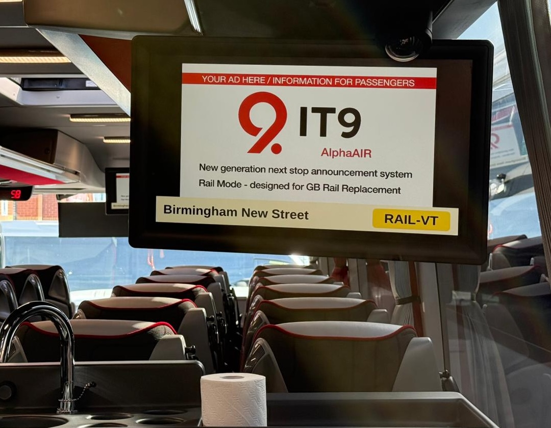 IT9 AlphaAIR onboard audio-visual announcement system in Rail Mode showing next stop Birmingham New Street on a coach passenger display, compliant with PSVAIR accessible information regulations